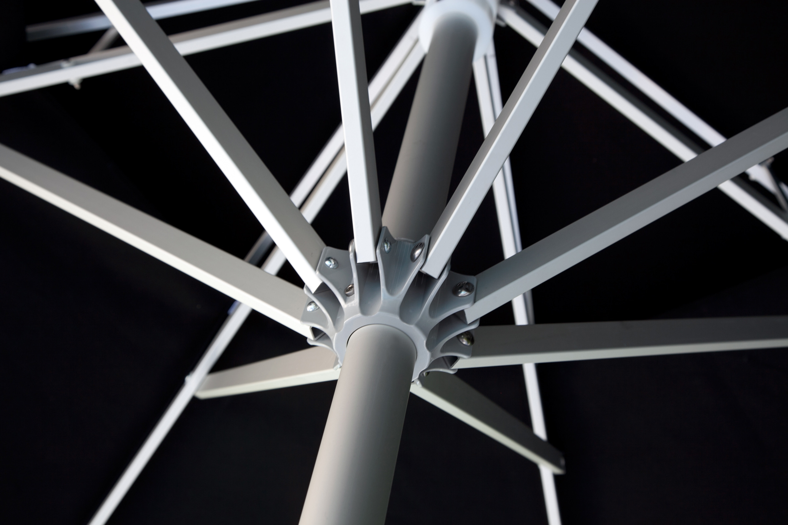 The cast hub and aluminium struts of a Samara umbrella, seen from beneath a black canopy.