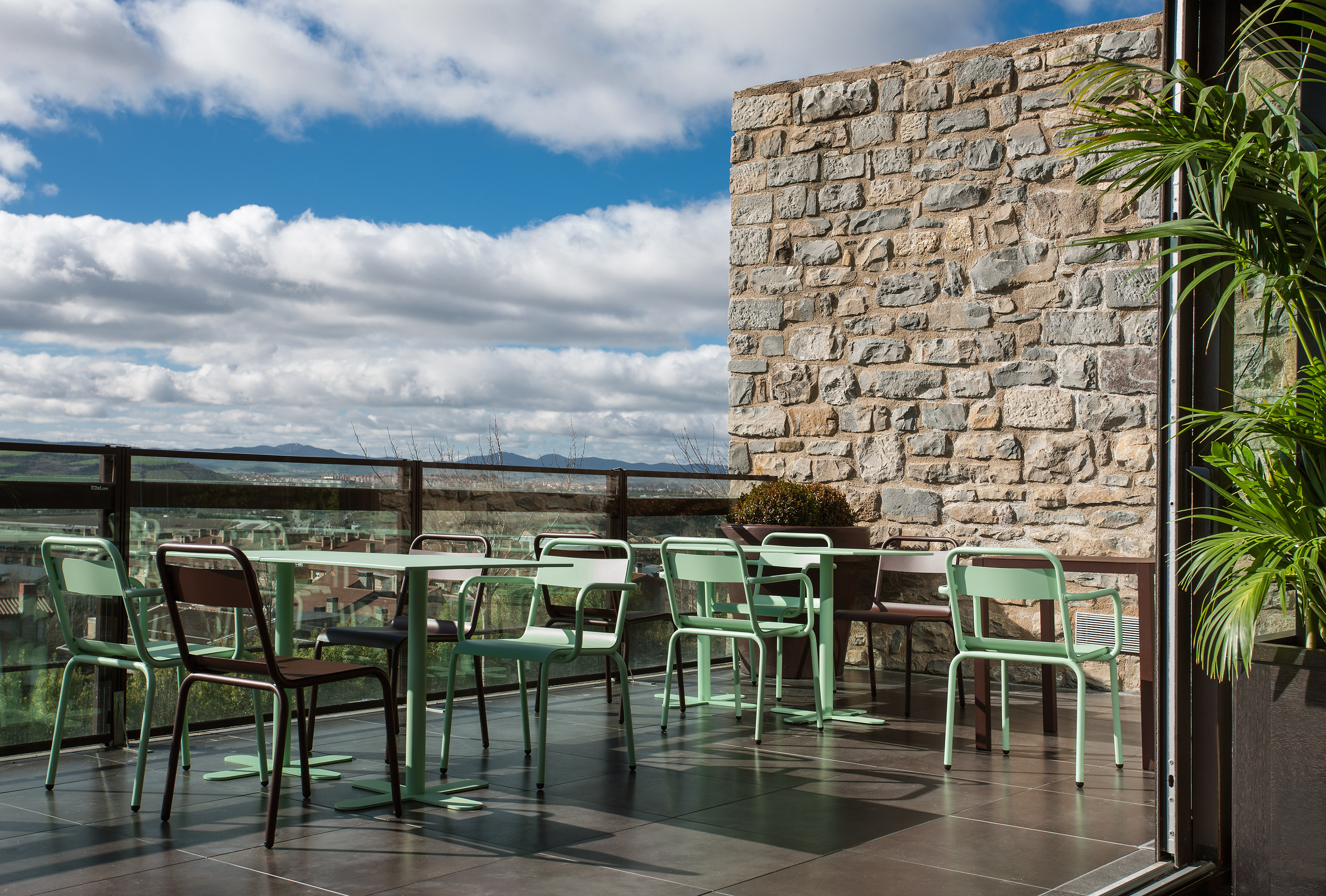 Steel chairs and a small table on a stone terrace.