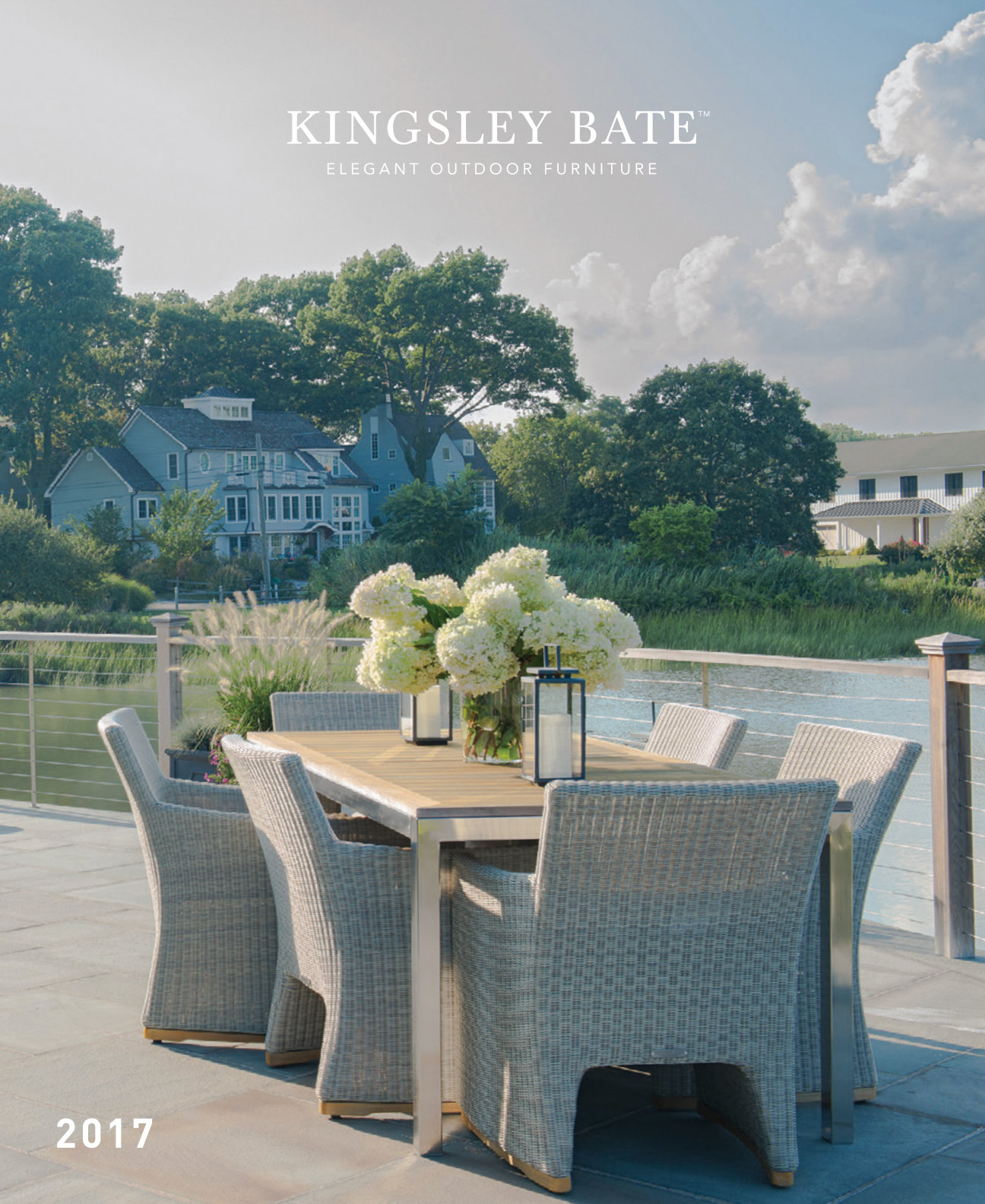 All-weather wicker dining set on a coastal lawn with hydrangeas behind