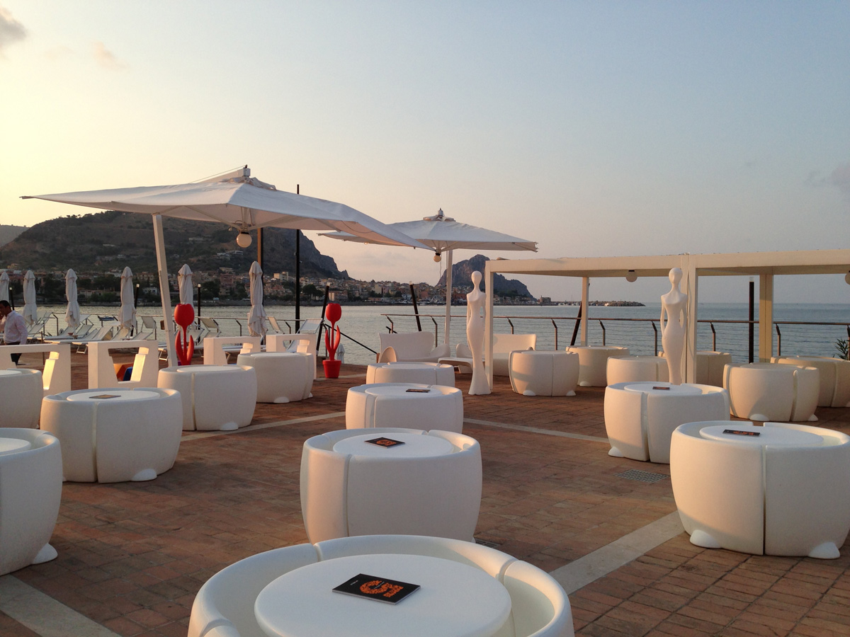 Lucy chairs, a Lucy sofa and a pair of Penelope statues, on a restaurant terrace at dusk