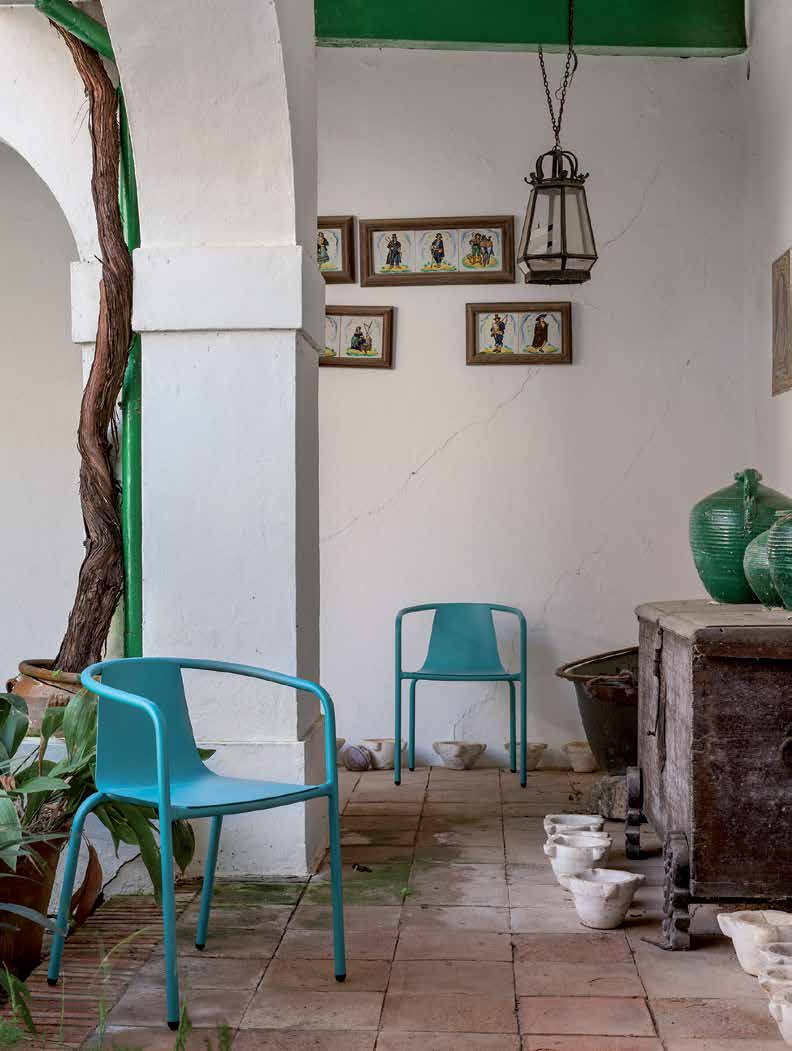 Turquoise stacking armchairs in a whitewashed Andalusian courtyard, terracotta tiles and old ceramic urns — iSiMAR catalogue photography