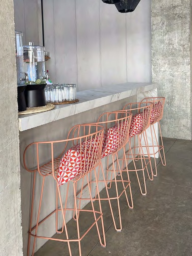 Four coral wire bar stools with red-and-white patterned cushions, lined at a marble-topped counter — iSiMAR catalogue photography