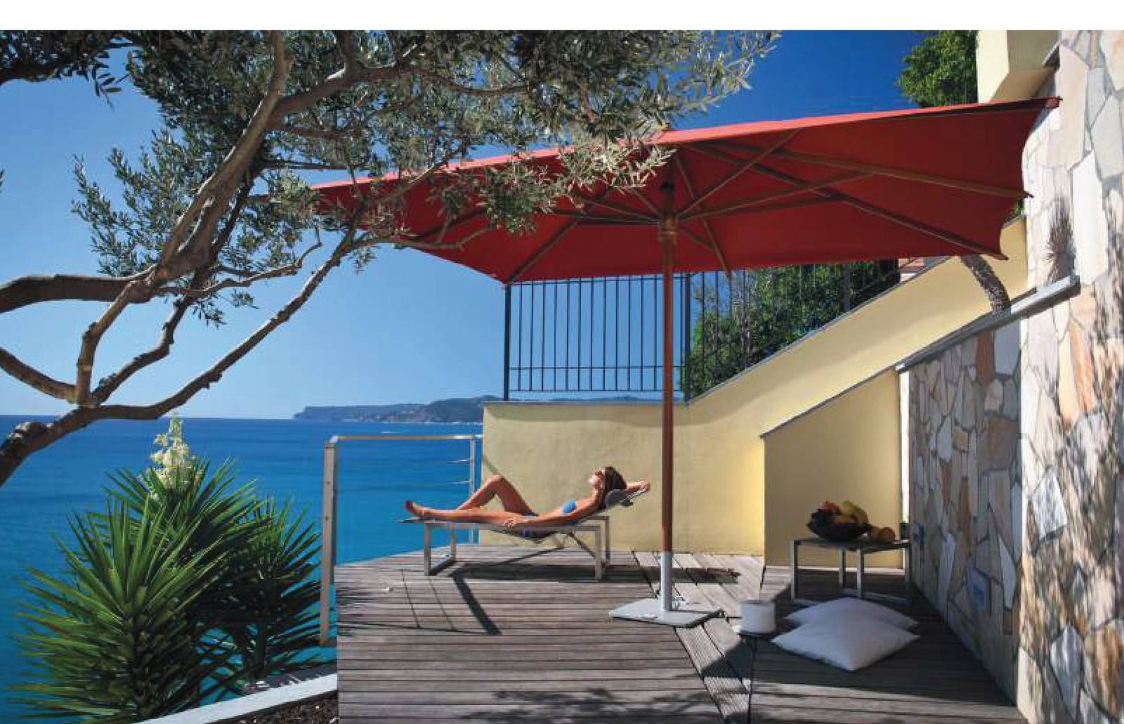 cantilever canopy in red shading a terrace lounger overlooking the coast