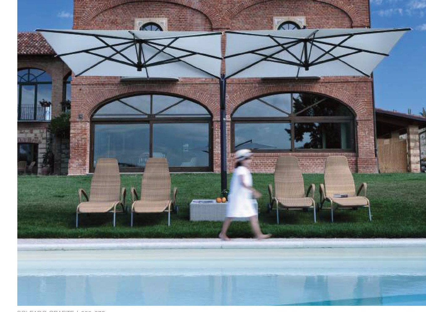 twin-head double-cantilever canopy in white shading loungers beside a brick building