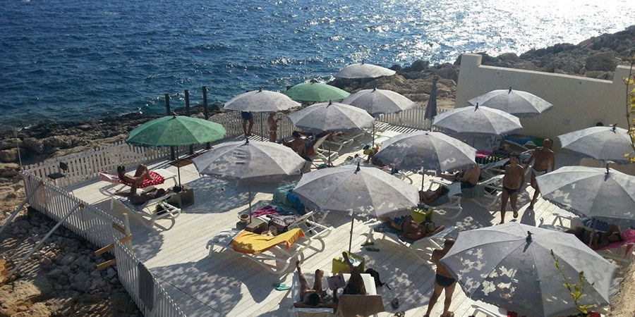 Grey and green lace-pattern parasols over a seaside sundeck, seen from above