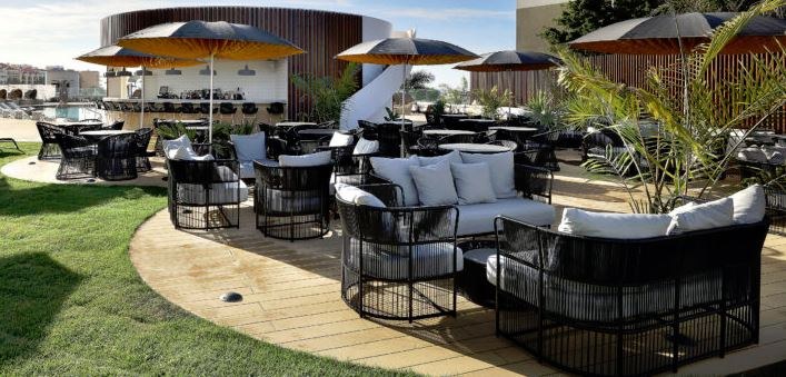 Round parasols in black with a yellow underside, shading a rooftop bar terrace